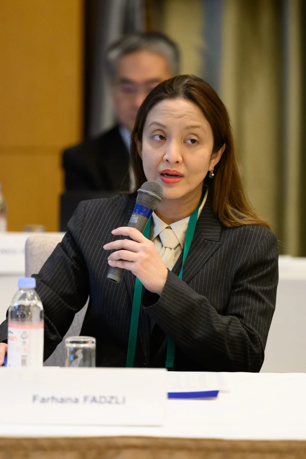 Dr Farhana Fadzli holding a microphone during a professional discussion